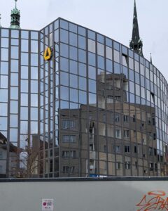 Spiegelung eines historischen Turms in der modernen Glasfassade eines Gebäudes in Halle an der Saale – wenn sich Altes im Neuen spiegelt