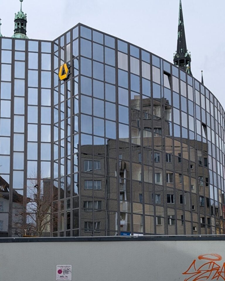 Spiegelung eines historischen Turms in der modernen Glasfassade eines Gebäudes in Halle an der Saale – wenn sich Altes im Neuen spiegelt