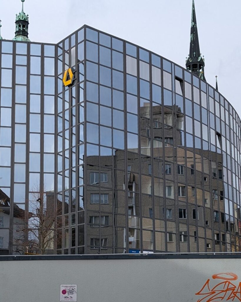 Spiegelung eines historischen Turms in der modernen Glasfassade eines Gebäudes in Halle an der Saale – wenn sich Altes im Neuen spiegelt