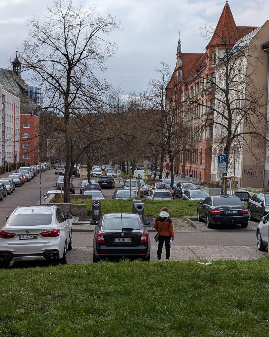 Blick über den terrassierten Parkplatz am Johannesplatz in Halle (Saale), rechts das markante rote Backsteingebäude der Johannes-Schule vor herbstlicher Kulisse.