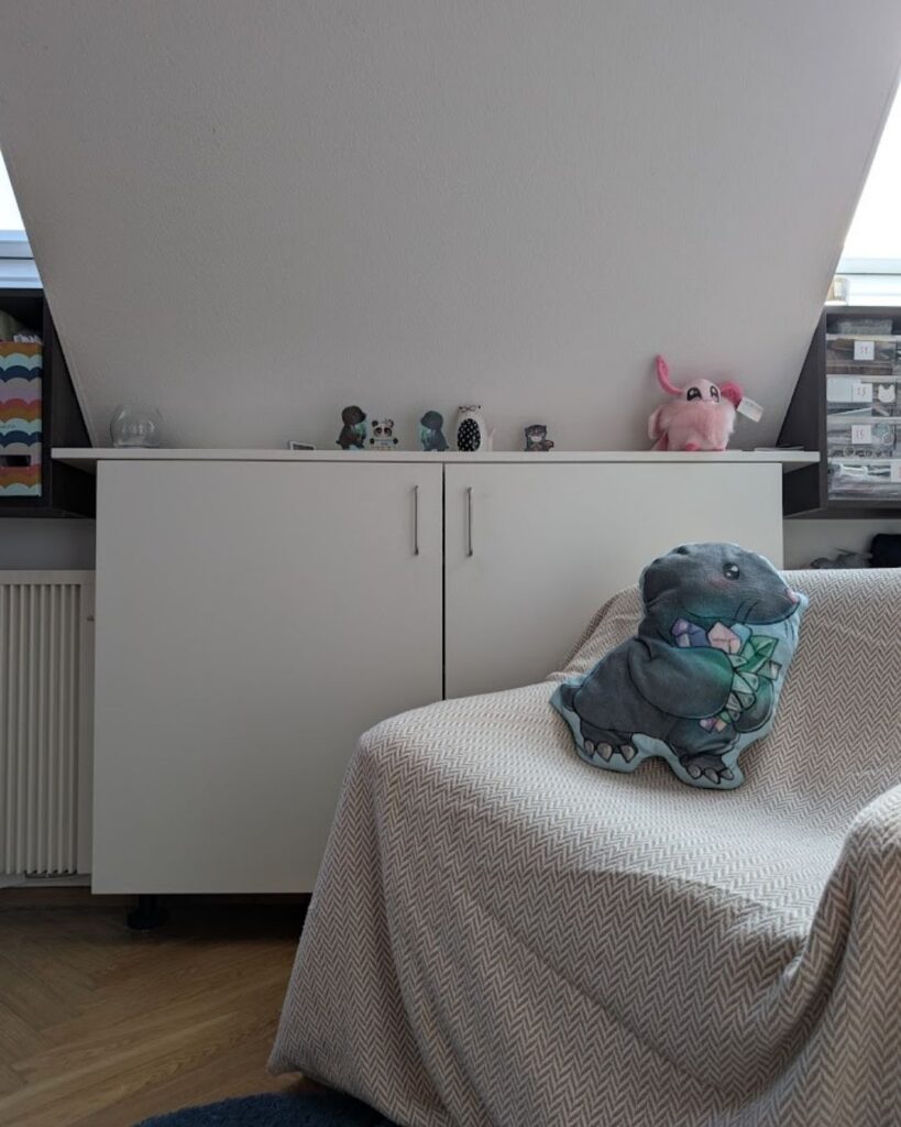 Ein gemütlicher Sessel vor einem Regal mit einer riesigen Auswahl an bunten Wollknäueln, bereit für ein neues Häkelprojekt