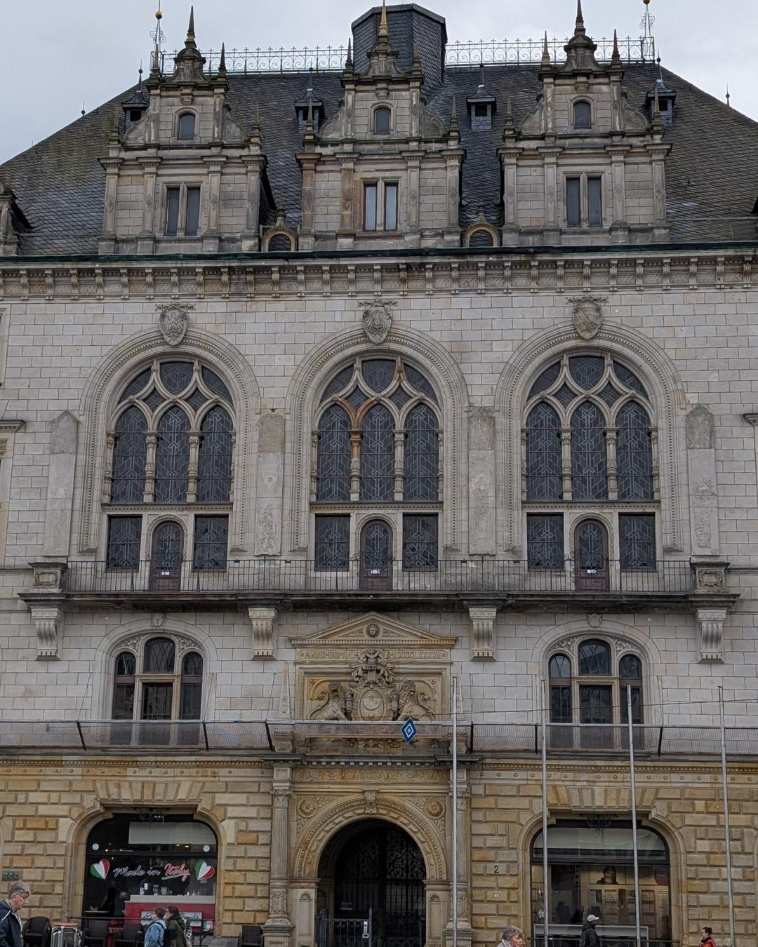 Die prachtvolle Fassade des Stadthauses in Halle (Saale) am Marktplatz mit drei großen neogotischen Maßwerkfenstern, aufwendigen Giebeln und einem historischen Portal mit Wappen.